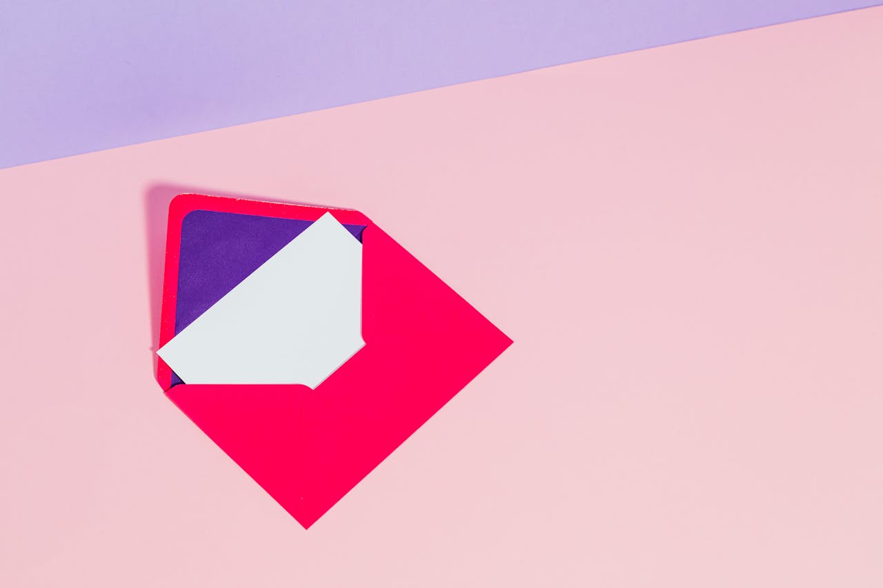 Open pink envelope on a pastel background with copy space, ideal for creative design uses.